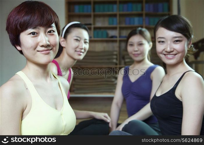 Four friends talking and smiling in a yoga studio