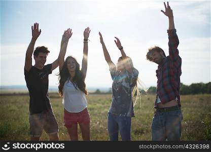 Four friends with arms raised, smiling