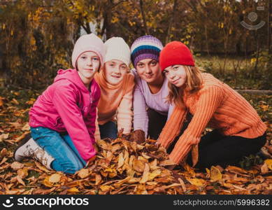 Four girls playing with autumn leaves and smiling. Girls playing with leaves