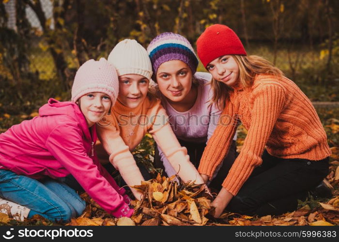 Four girls playing with autumn leaves and smiling. Girls playing with leaves