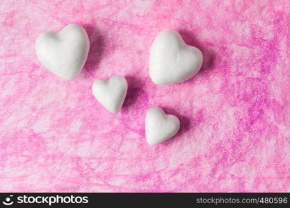 Four hearts of styrofoam on pink background