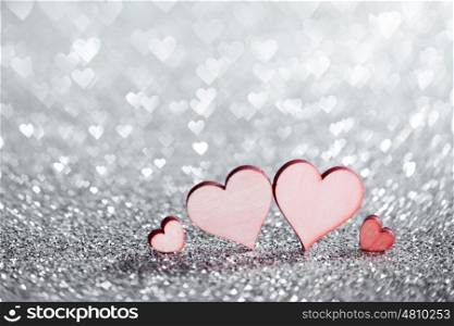 Four hearts on glitters. Four wooden hearts on silver glowing bokeh hearts background for Valentines day