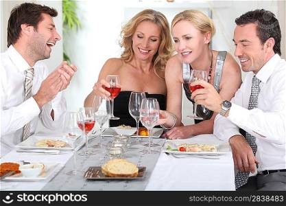 Four joyful people at the start of a posh dinner.