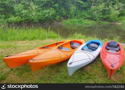 four kayaks on the Bank of the river, sports kayaks on the shore of the pond. sports kayaks on the shore of the pond, four kayaks on the Bank of the river