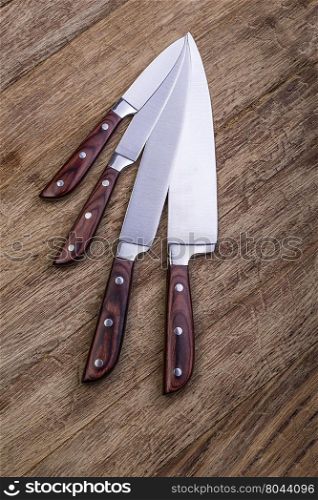 four kitchen knifes on wooden board