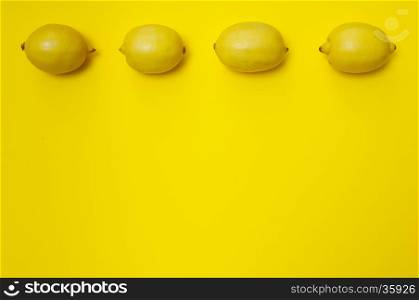 Four lemons in a row on yellow background with copy space