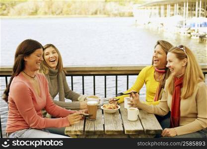 Four mature women sitting at a sidewalk cafe and laughing