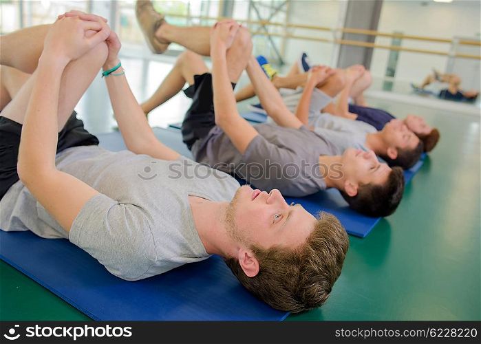 Four men exercising, bending their left knees forward