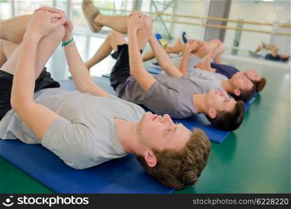 Four men exercising, bending their left knees forward
