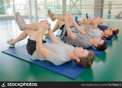 Four men on floor exercising, leg bent