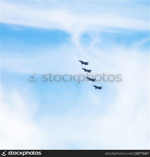 four military fighter jets in cloudy blue sky