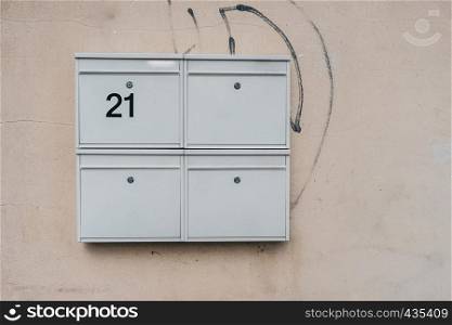 Four modern mailboxes at plastered creamy wall