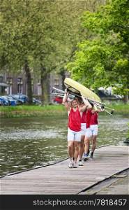 Four oarsmen carrying a rowing boat back to the boathouse after winning a race.