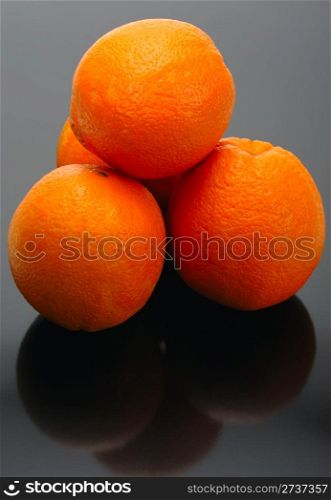 Four oranges and their reflection on a black background