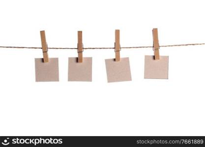 Four paper blank notes hanging on the rope isolated on white background. Blank paper notes on white