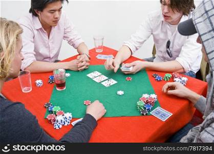 Four people around a table during a poker game