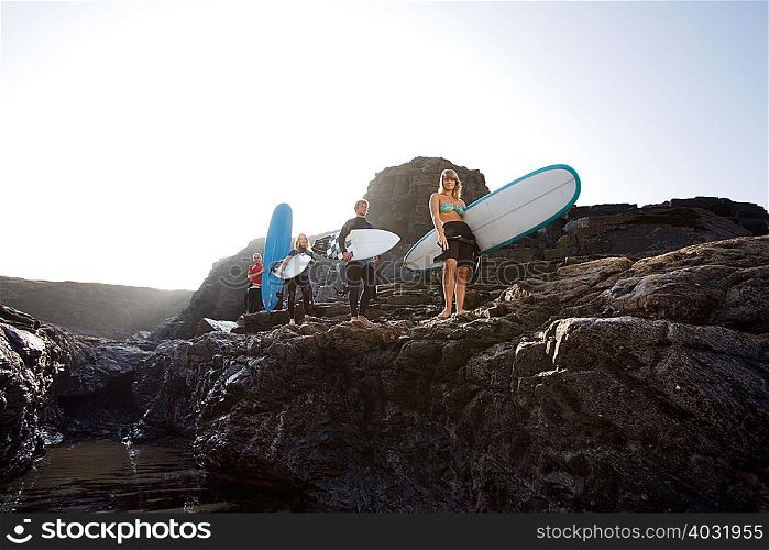 Four people carrying surfboards
