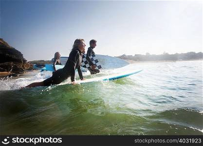 Four people going out to surf smiling