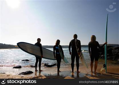 Four people holding surfboards