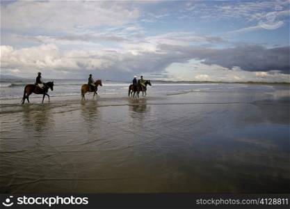 Four people horseback riding on the beach, Sligo, Republic of Ireland