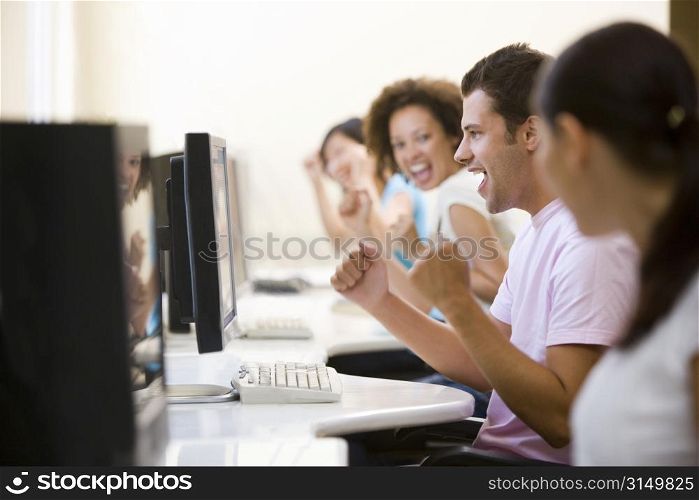 Four people in computer room cheering and smiling