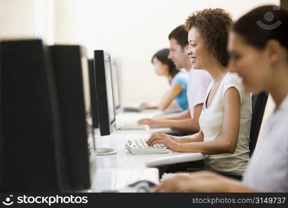 Four people in computer room typing and smiling