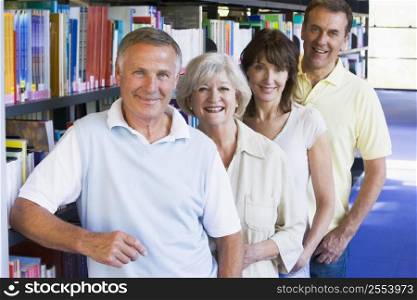 Four people in library standing by bookshelves