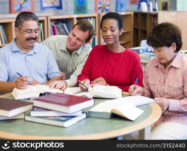 Four people in library with books and notepads (selective focus)
