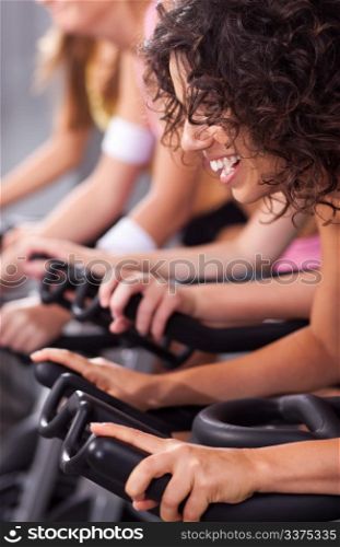 Four people on bicycles in a gym or fitness club for a workout.