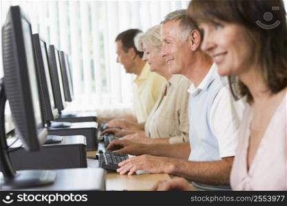 Four people sitting at computer terminals (selective focus/high key)