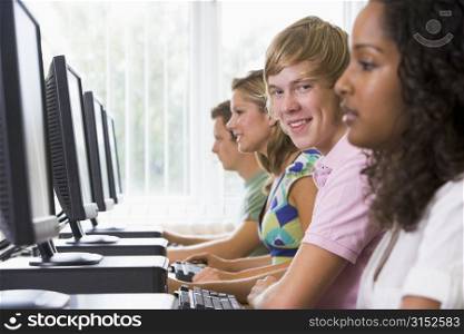 Four people sitting at computer terminals (selective focus/high key)