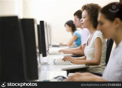 Four people sitting in computer room typing
