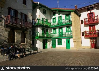 Four people sitting on a bench in a courtyard, Spain