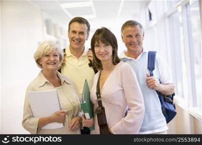 Four people standing in corridor with books (high key)