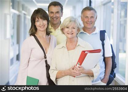 Four people standing in corridor with books (high key)
