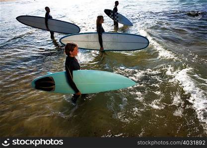 Four people standing with surfboards
