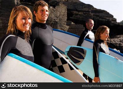 Four people standing with surfboards