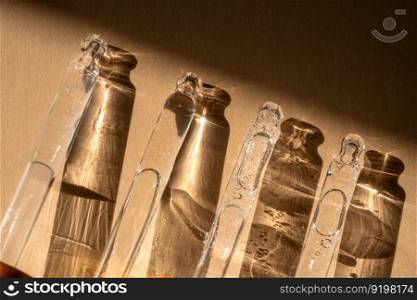Four pipettes of cosmetic gel on a beige background. Demonstration of the texture of the product.. Four pipettes of cosmetic gel on a beige background.