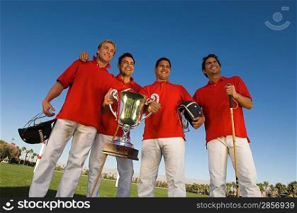 Four polo players with trophy