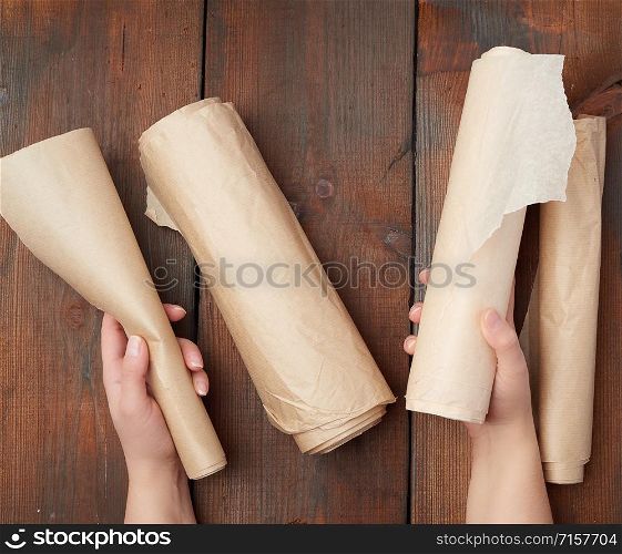 four rolled rolls of brown parchment paper on a wooden surface, top view