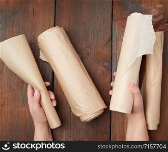 four rolled rolls of brown parchment paper on a wooden surface, top view
