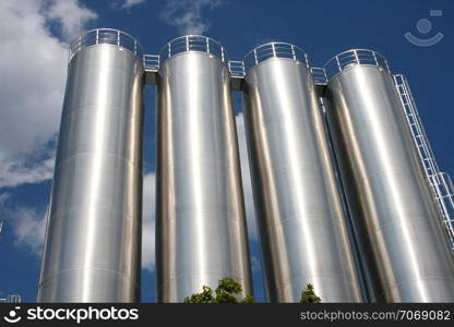 four round industrial tanks with blue sky as background