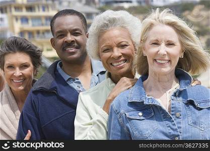 Four senior adults stand in a row smiling at camera