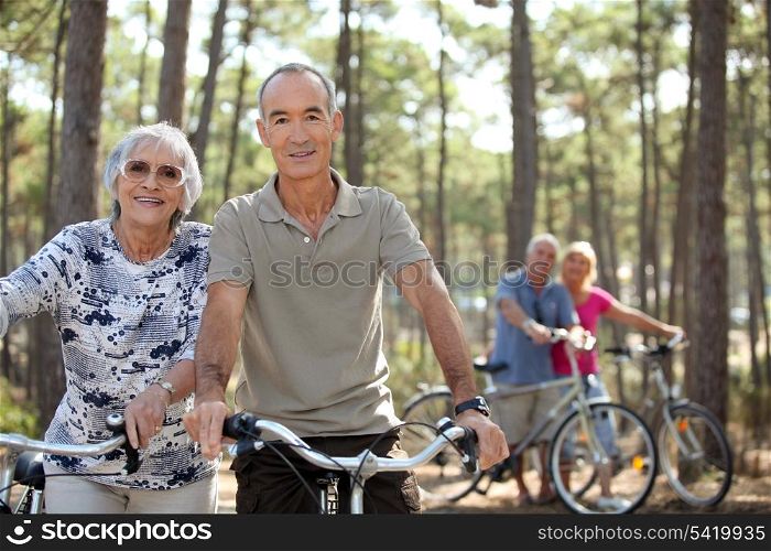four senior people doing bike in a pine forest