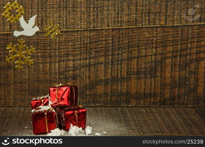 Four small decorative snow covered Christmas gifts ,gold stickers snowflakes and white pigeon on old wooden background.Interesting Christmas decoration,greeting card with copy space. Horizontal view