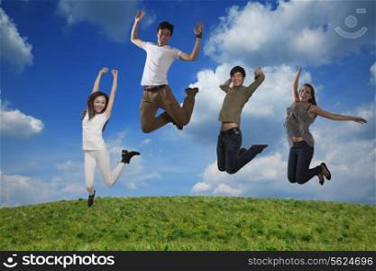 Four smiling friends jumping in mid-air, sky and cloud background