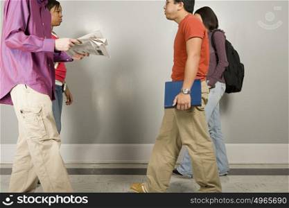 Four students walking along corridor