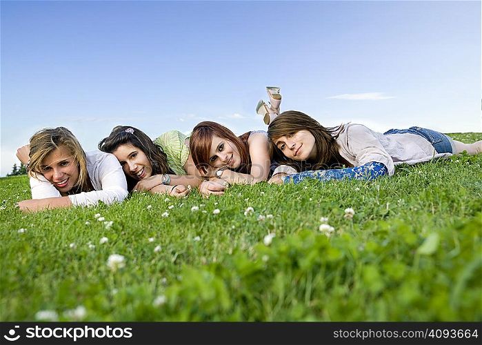 Four teen girls portrait laying on grass