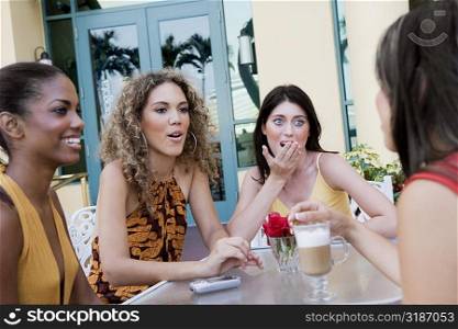Four teenage girls sitting together and gossiping