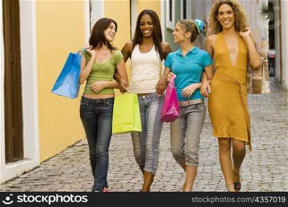 Four teenage girls walking in an alley and holding shopping bags